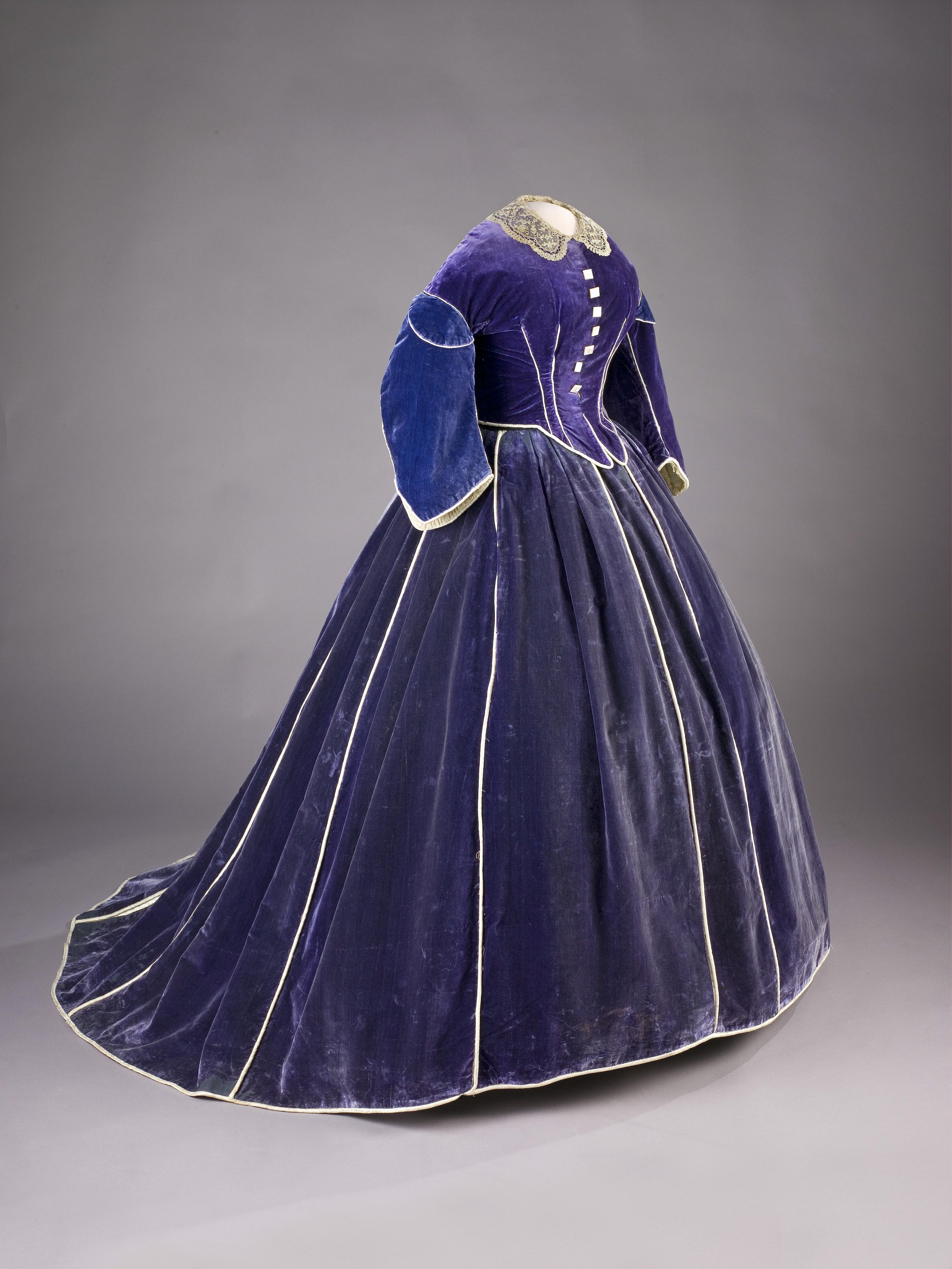 Half-profile photo of a floor-length blue velvet gown on a dressmaker's mannequin