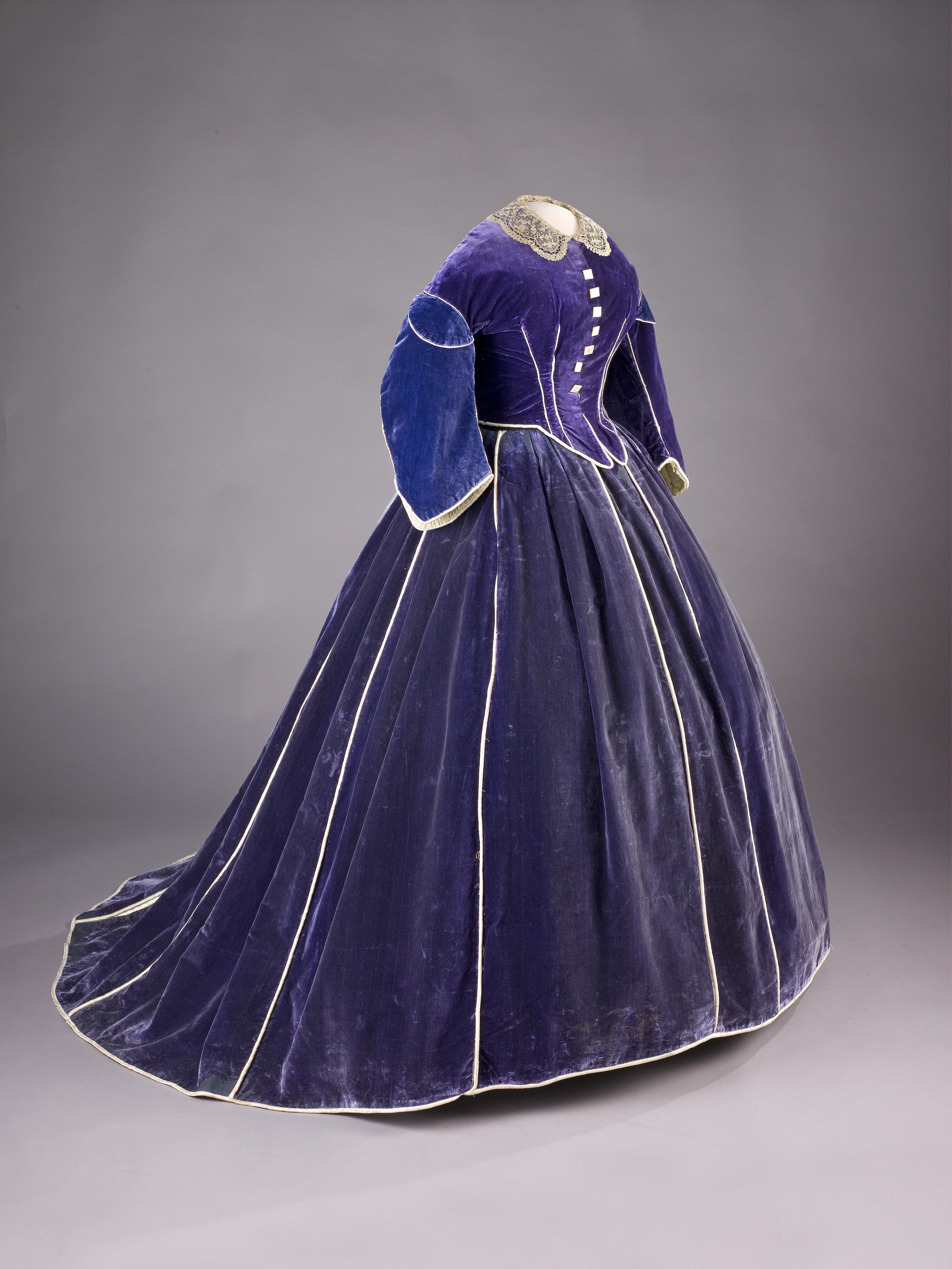 Half-profile photo of a floor-length blue velvet gown on a dressmaker's mannequin